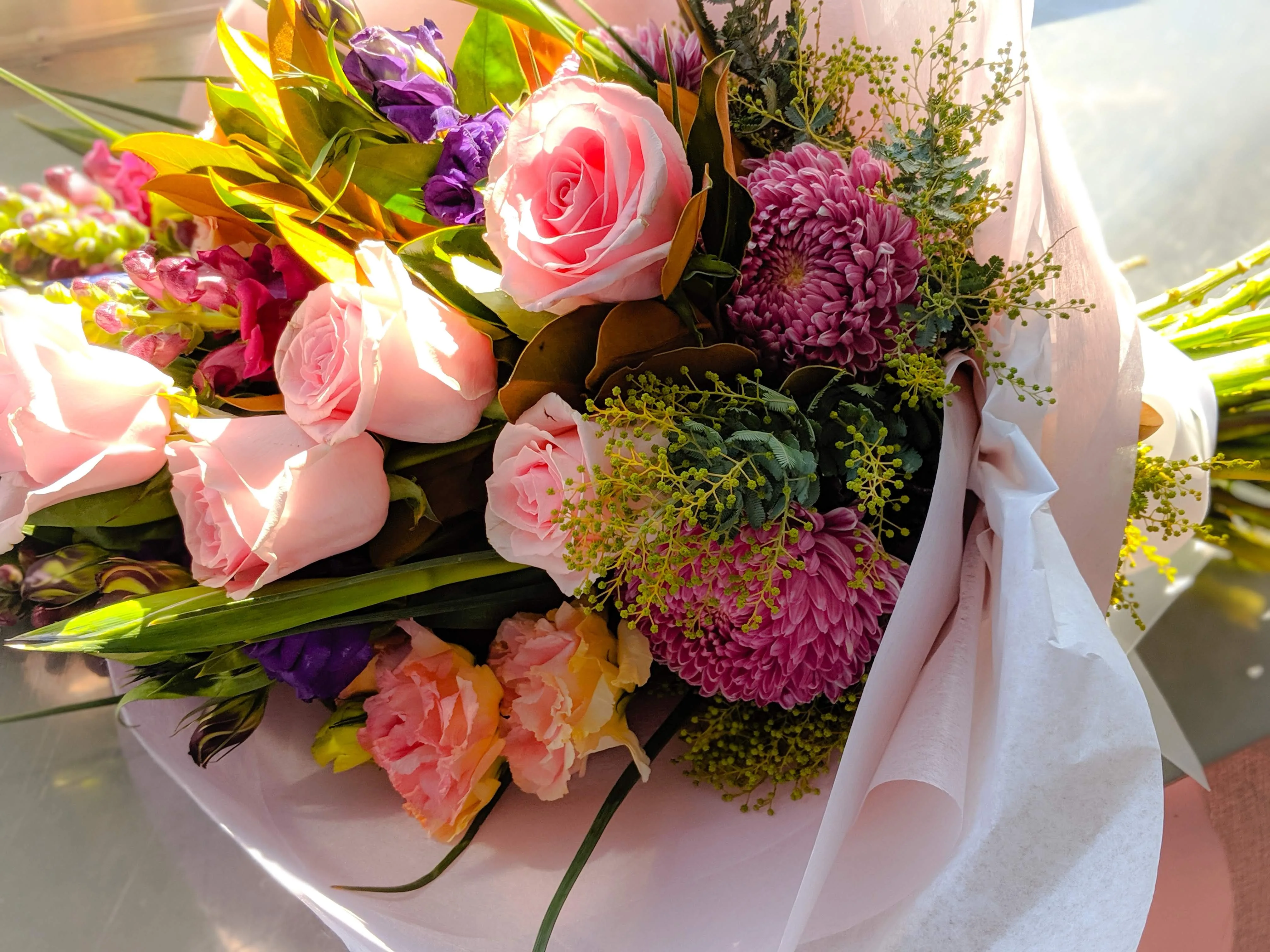 Sunlit pink roses, magenta chrysanthemum and golden wattle arrangement